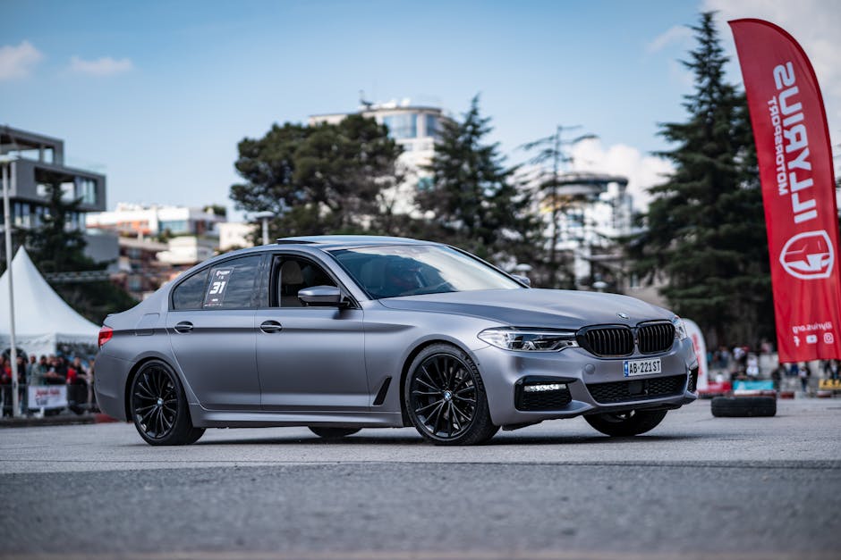 A stylish silver BMW parked on a city street during a car event, showcasing modern design