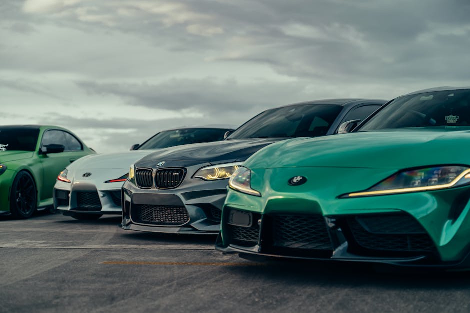 Three sleek sports cars parked outdoors under a dramatic sky, showcasing modern automotive design