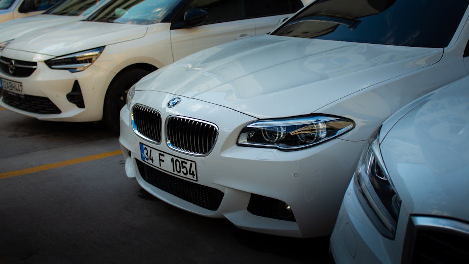A sleek white BMW car parked in an urban setting alongside other vehicles