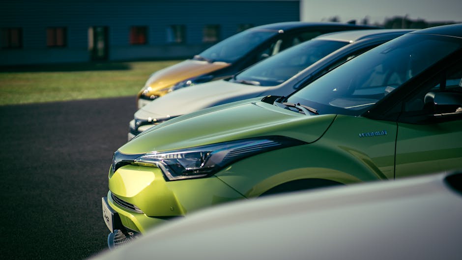 A row of brightly colored cars parked outdoors under daylight, showcasing their vibrant paint and shiny exteriors