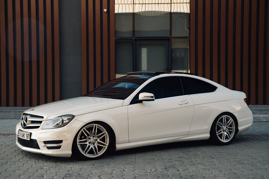 Sleek white Mercedes coupe parked against modern building facade, perfect for car enthusiasts