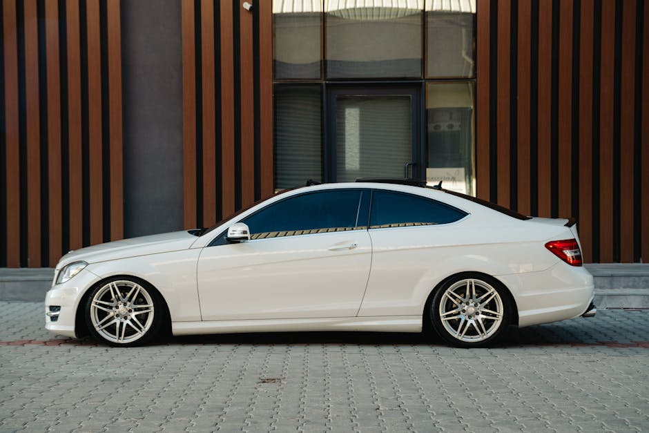 Elegant white coupe car parked outdoors against a modern building facade